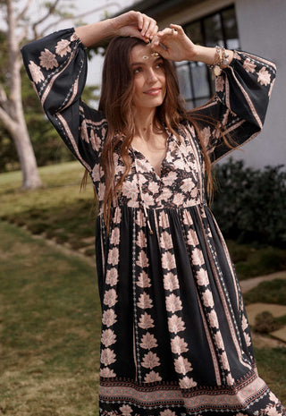  wearing a long-sleeve boho-style dress with a black base and beige floral patterns.